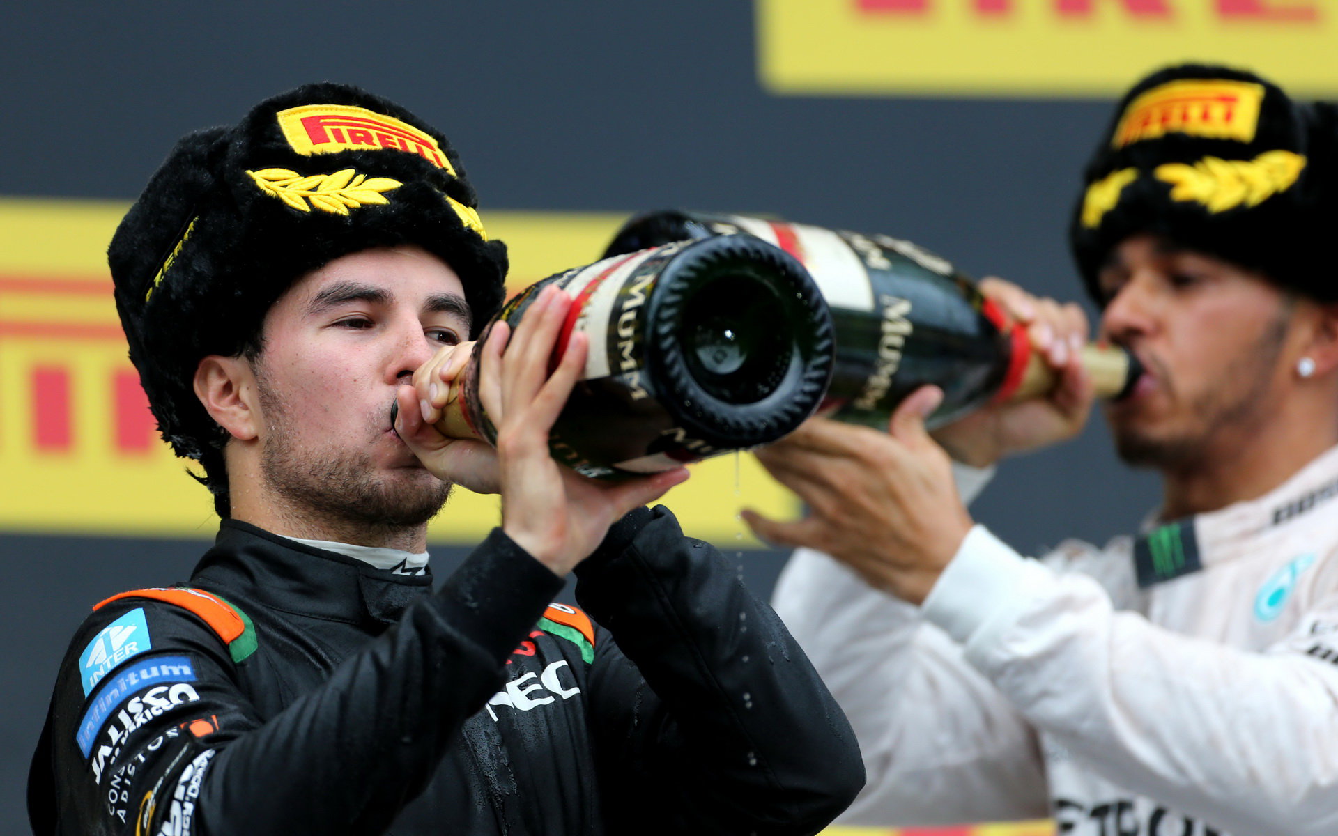 Sergio Pérez a Lewis Hamilton popíjí šampaňské na pódiu v Soči