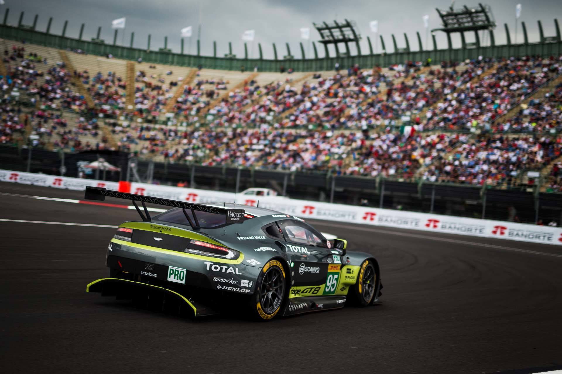 Aston Martin Vantage #95 posádky Nicki Thiim, Marco Sorensen projíždí basebalovým stadionem na trati v Mexiku