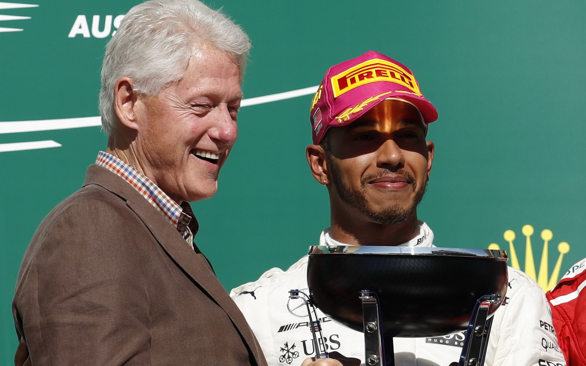 Bill Clinton a Lewis Hamilton na pódiu po závodě v Austinu
