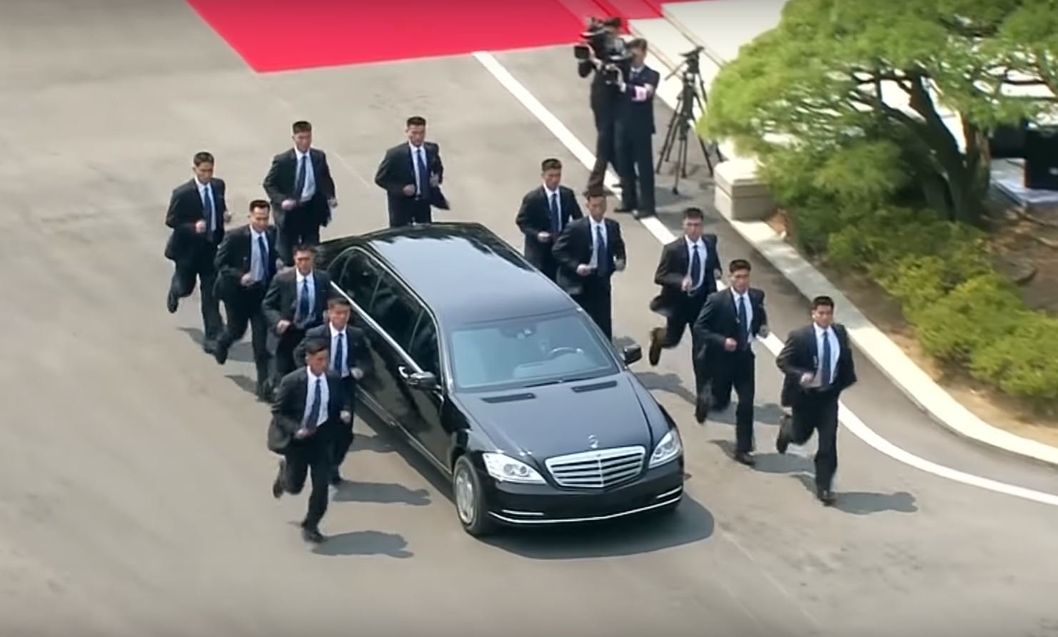 Kim Čong-Un a jeho speciální kolona. Limuzínu s diktátorem obklopují běžící bodyguardi
